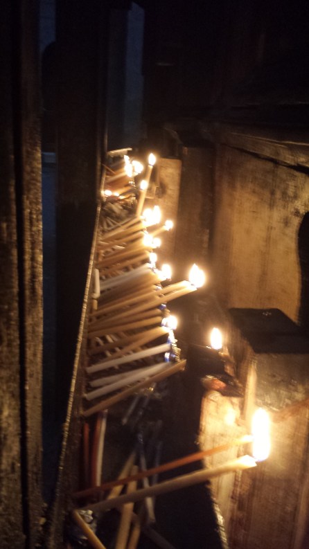 Prayer tapers left by Pilgrims line the exterior of the Aedicule, illuminating the shrine 